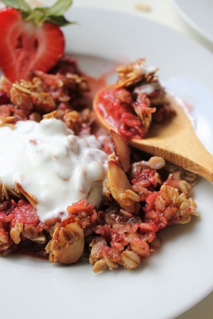 close up of a slice of strawberry crisp with a dollop of greek ypgurt on top