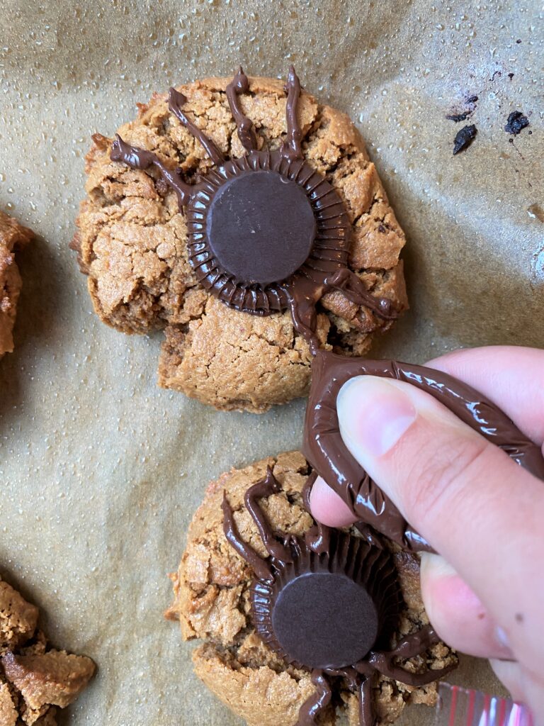 making spiders out of chocolate on the vegan gluten free peanut butter cookies