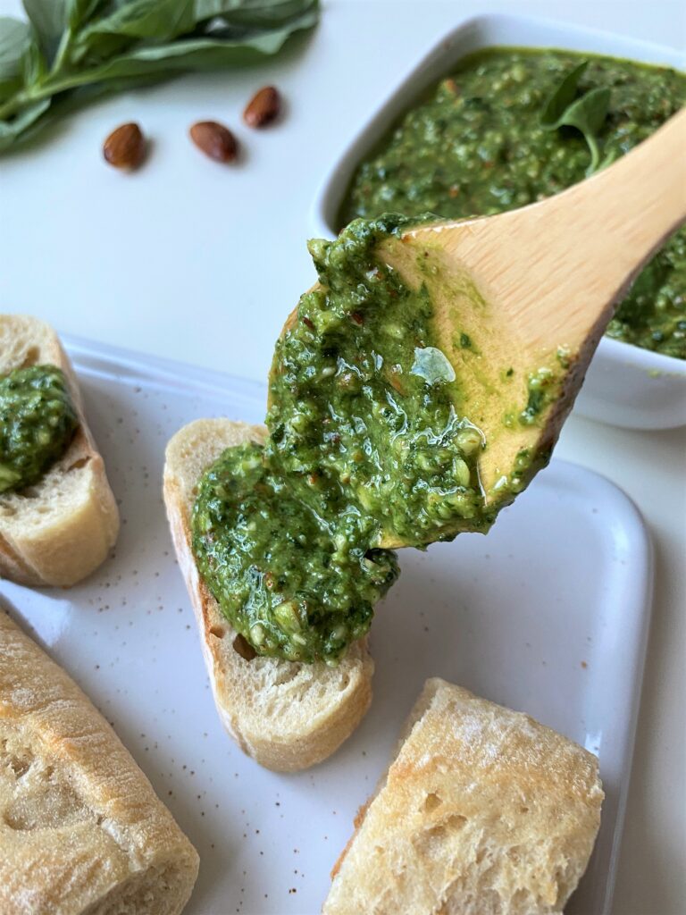 spooning some fresh pesto onto a fresh baguette